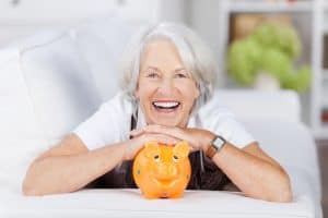 Lachende Seniorin mit Sparschwein