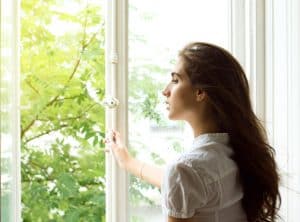 Junge Frau an offenem Fenster