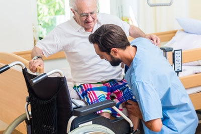 Altenpfleger und Senior mit Rollstuhl
